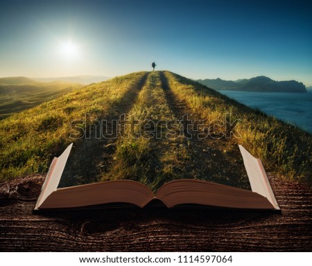 Girl hiker with backpack and trekking sticks standing on a mountain top against sunset on the pages of an open magical book. Majestic landscape. Travel concept. Royalty-Free Stock Photo #1114597064