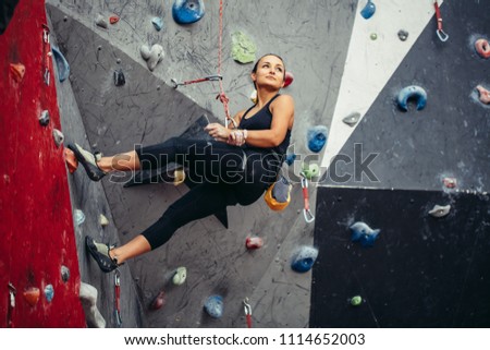 Sporty successful business woman being busy at her hobby-bouldering. Well equipped woman training in a colorful climbing gym, preparing to summer mountain ascend