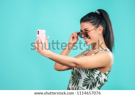 close up side view photo of happy female tourist in sunglasses taking a selfie