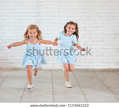 Two small girls playing and running indoors together