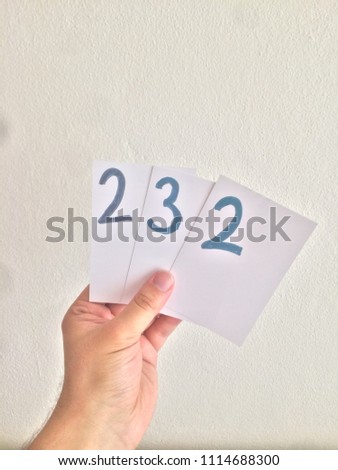Handmade numbers that holding by hand on white paper.