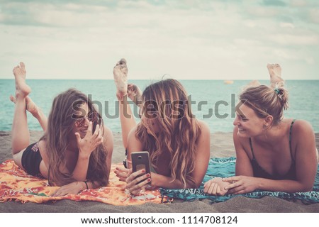 three nice girls use mobile phone technology to take pictures at the beach relaxing and enjoying lifestyle and vacation leisure. outdoor modern activity with internet and social media