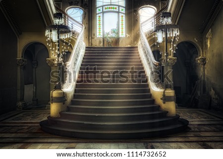 Entrance with symmetrical stairs of an abandoned casino. Sunlight shines through the windows and lights the darkness. Royalty-Free Stock Photo #1114732652