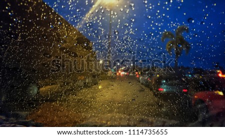 Blured drops of rain on the window on the background of the night bokeh. Abstract background with defocused lights. Focus on few drops due to the shallow depth of field. 