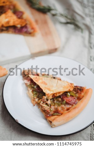 Fresh italian pizza. Food photography for design. Mexican pizza with chips, onion, hot jalapeno pepper on thin classic dough. Closeup photo of slice. Craft paper and wooden background.