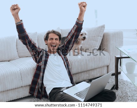 happy young man exults with his dog sitting in the living room