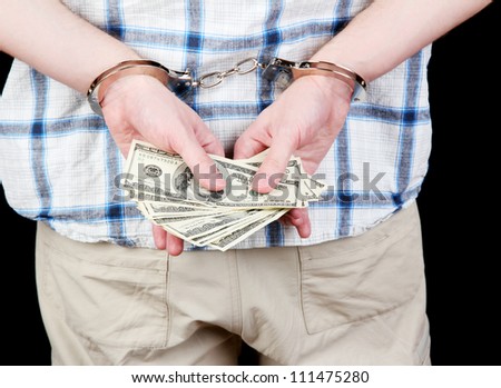 man in handcuffs is holding dollars, on black background