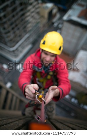 Industrial rope access construction worker  using ascender clipping into the Nylon abseiling rope with blurry picture at the back ground high rise building in Sydney city CBD, Australia 