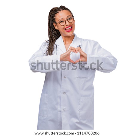 Portrait of a young black doctor woman making a heart with hands, expressing the concept of love and friendship, happy and smiling