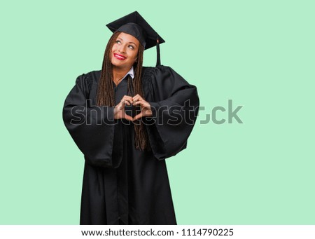 Young graduated black woman wearing braids making a heart with hands, expressing the concept of love and friendship, happy and smiling