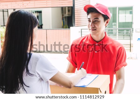 Woman putting signature in clipboard on cardboard box to receiving package with delivery man in red uniform.courier service concept