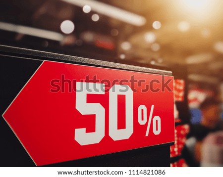 Red Label with white text 50% off sale in  shopping store against blurred bokeh and lighting background. Discount Promotion advertise concept.