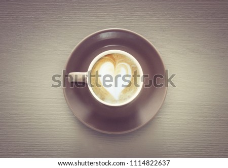 image of coffe cup with foam of heart shape over wooden table