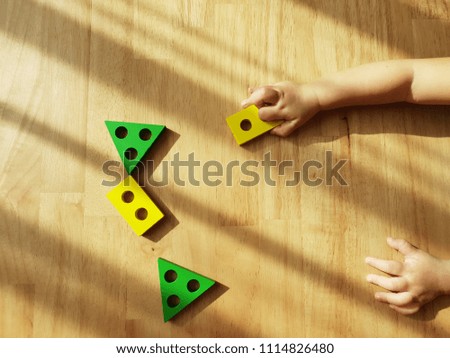Baby kid is playing colourful learning toy  on wooden background. Picture of a Classic Toy for Young Child.