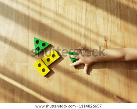 Baby kid is playing colourful learning toy  on wooden background. Picture of a Classic Toy for Young Child.