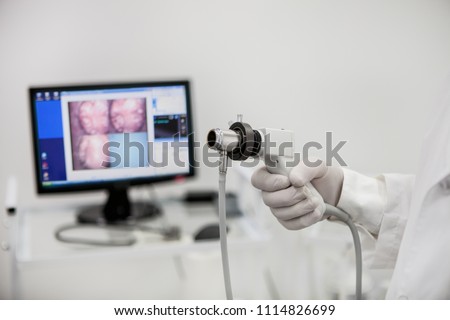 Videorecdoscope for visual diagnosis in the hand of a proctologist on the background of an unsharpened monitor.