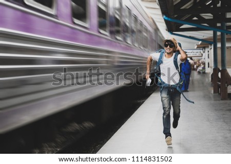 Tourist with bag running behind the train, A man runs for a moving wagon, Backpacker hurries for train departing from the station, Journey to the last minute Royalty-Free Stock Photo #1114831502