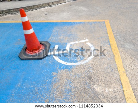 traffic cone on Disabled parking. International Symbol of painted in bright blue on center parking space. Facilitates the provision of parking for the disabled.
