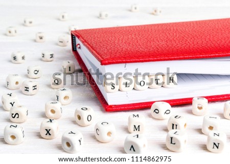 Word Sloth written in wooden blocks in red notebook on white wooden table. Wooden abc.