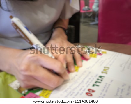 blur photo of a woman hand hold a pen writing on farewell card that full of farewell message wish