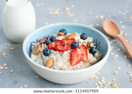 Oatmeal porridge in a blue bowl with berries and nuts. Porridge oats bowl with strawberries blueberries and almonds. Healthy eating, dieting, vegetarian food concept Royalty-Free Stock Photo #1114907909
