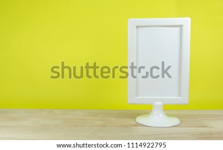 Photo frame white vintage on wooden table background yellow,copy space.