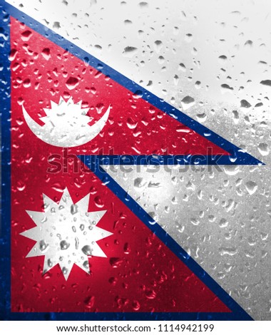 Texture of Nepal flag on the glass with drops of rain.