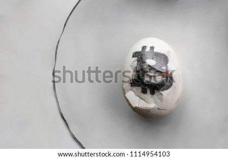 White egg with currency sign. Bitcoin logo on a crushed dirty white egg on the white platre. Gray backgrounds