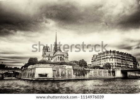 View of the island of Cité and Notre Dame from the river Seine, in vintage style, monochrome and high grain of the film, against the background of the expressive cloudy sky. Paris, France.