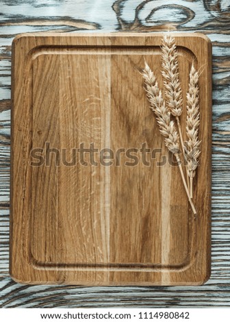 Chopping board rye ears on vintage wooden surface.