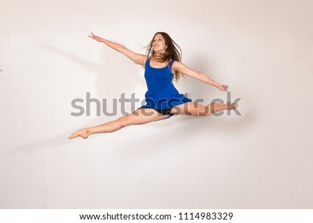 Acrobatic and funny jumps of a young woman in a photography studio session