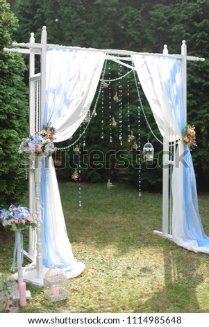 White wedding arch in garden. Concept of bridal decorations and elements.