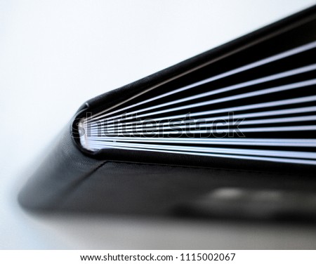Close up opened book page. Black cover, white background. Photobook with leather cover Royalty-Free Stock Photo #1115002067