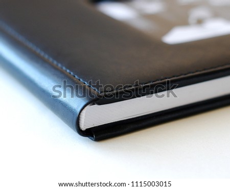 Close up opened book page. Black cover, white background. Photobook with leather cover