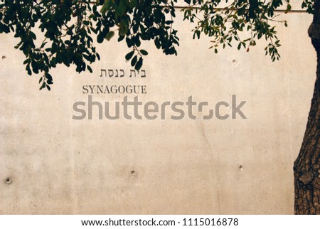 the inscription Synagogue on the wall in the shade of a tree. English, Hebrew. Old City, Jerusalem, Israel Royalty-Free Stock Photo #1115016878