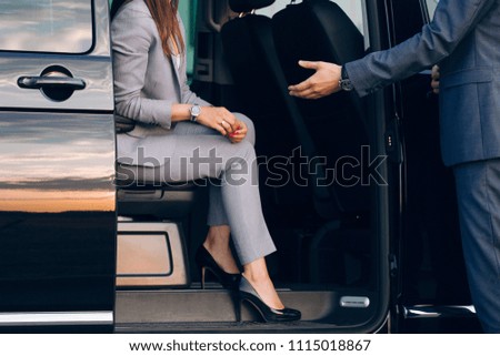 Business woman travelling in vip car transfer. Driver helping woman to get outside the car. Gentleman give a hand to the lady at the car Royalty-Free Stock Photo #1115018867