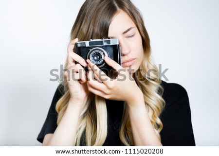 beautiful blond woman taking pictures on a retro camera, isolated studio photo on a background