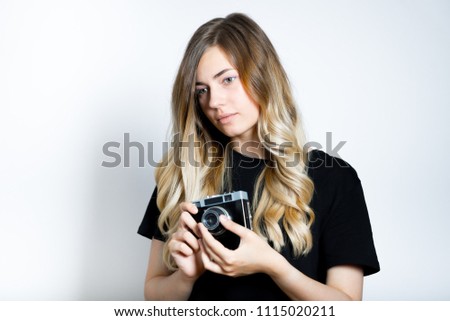 beautiful blond woman adjusting retro camera, isolated studio photo on background