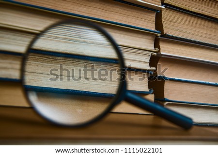 magnifier against pages of book. book shelf background. 