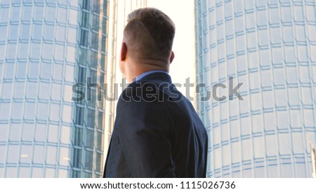 Young handsome businessman in suit, skyscraper background	