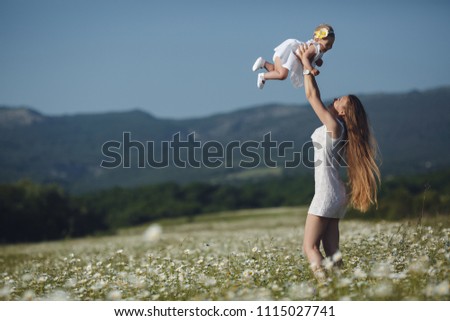 happy family in nature. woman with baby having fun in chamomile field