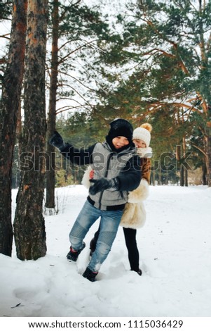 Teenager boy and girl having fun in winter forest full of snow