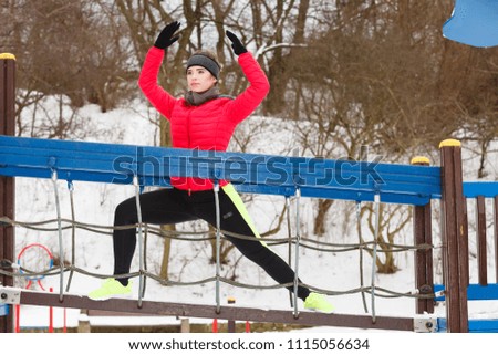 Workout in public park. Woman wearing warm sportswear urban street training exercising outside during winter.