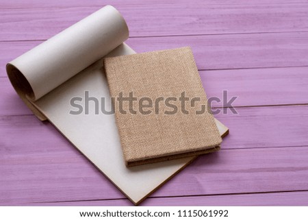 ์์Black brown notebook  isolated on violet tone wooden table background.