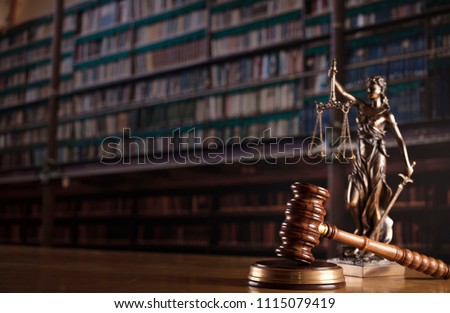 Law concept. Judge’s gavel, statue and scales of justice. Old courtroom library. Wooden desk.