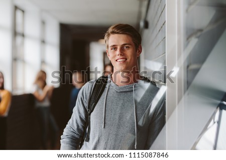 Portrait of teenage male student standing wall in corridor of a college. Caucasian male student in university campus. Royalty-Free Stock Photo #1115087846