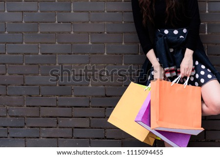 Asian portrait girl has happy and smiling with shopping colorful bags and grey brick wallpaper background.