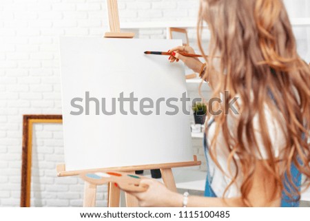 Pretty talented female painter painting on easel