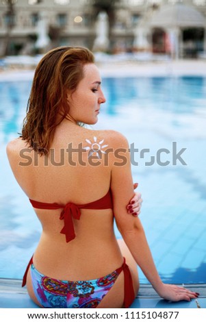 Young woman with sun shape on the shoulder holding sun cream bottle. Female  applying sunscreen. Skincare. Body Sun protection. Bikini  woman smear  moisturizing lotion on back.