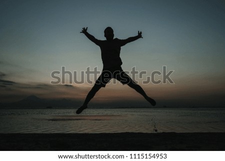 
Young man on vacation in the Gili Islands enjoying a colorful sunset in Indonesia. Jumping for the picture. Photograph and vacation.